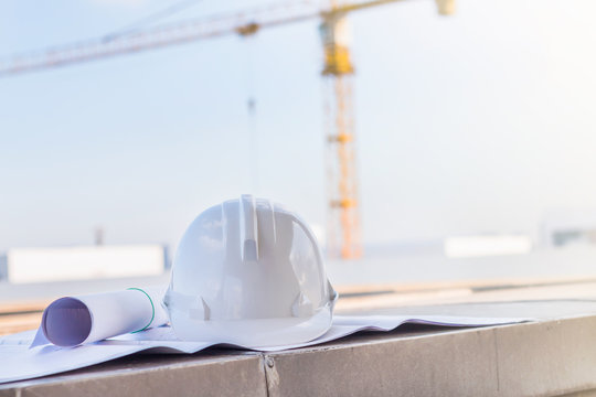 The white safety helmet and the blueprint at construction site w
