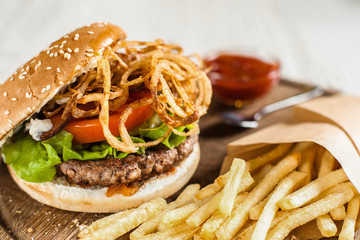 Restaurant serving of burger with fries and ketchup. Side view on catering platter with traditional american snack. Fast junk food, dining, fat eating concept