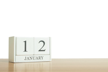 Closeup surface white wooden calendar with black 12 january word on blurred brown wood desk isolated on white background with copy space , selective focus at the calendar