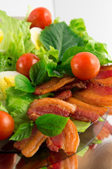 Plate of fried bacon, cherry tomatoes and herbs