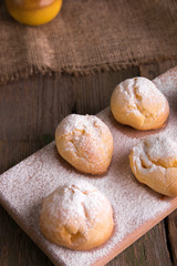 Profiteroles with powdered sugar on wooden background. Rustic style. Close up.