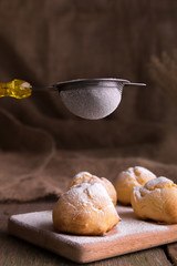 Process of decorating with icing sugar profiteroles. Rustic style.