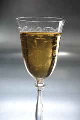 White wine in a glass on a metal / silver / light background 