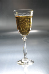 White wine in a glass on a metal / silver / light background 