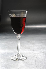 a glass of red wine on a metal / silver / light background 