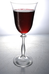 a glass of red wine on a metal / silver / light background 