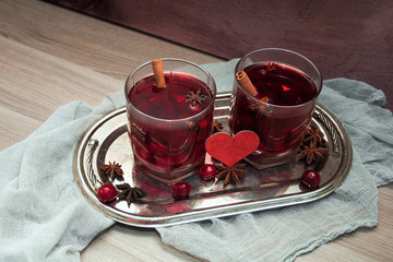 two glasses of mulled wine with cherries, cinnamon and star anise for lovers on silver vintage tray with red heart. concept for a romantic anniversary, Valentine's day