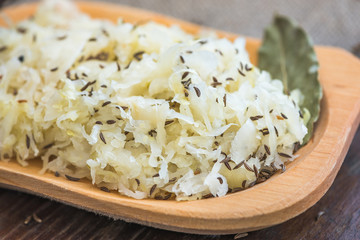 Closeup of Sour Cabbage with Cumin and Bay Leaf on Wooden Plate
