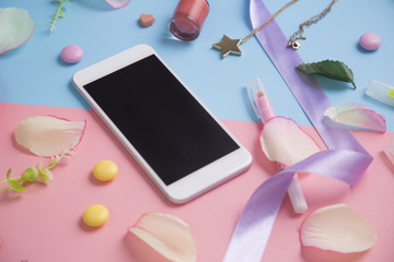 Smartphone with pink petals on pastel background.