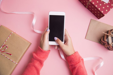 Women hand use smartphone on pink background.