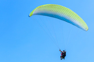 Paragliding in blue sky, instructor and beginner