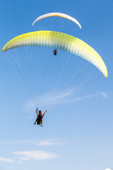 Amateur paragliders in blue sky with clouds
