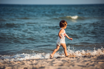 joyful little child running along the shore of the beach