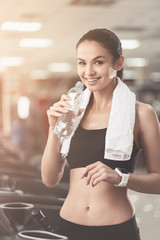 Joyful woman drinking water after sport exercises