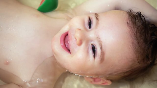 cute little baby girl lying in bath and look in the camera