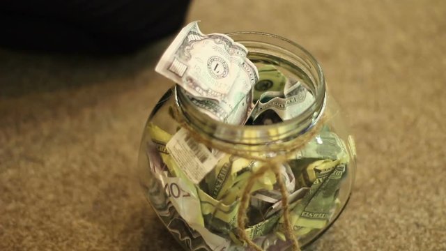 child gets bank notes from a glass jar with chopsticks