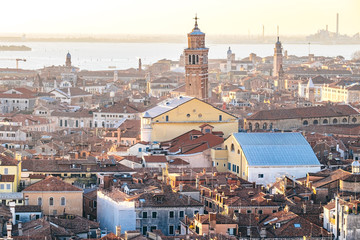 Fototapeta na wymiar Aerial view of Venice, Italy, at sunset with rooftops of buildings and warm sunlight.