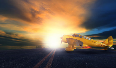 Fototapeta na wymiar old yellow propeller plane on airport runway with sunset sky bac