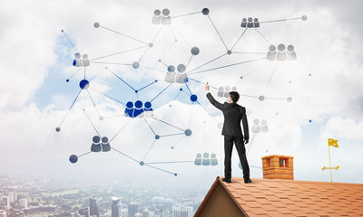 Businessman on house roof presenting networking and connection concept. Mixed media