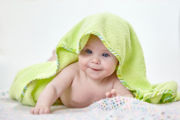 happy baby under a green towel after bathing