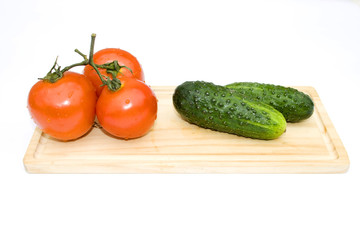 Cucumbers and tomatoes disposed on piece of wood