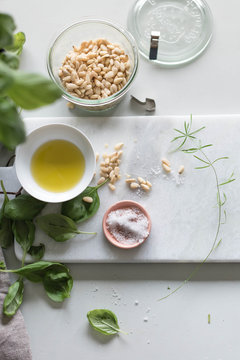 Bowl of pine nuts, basil, olive oil on table