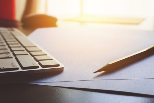 office workplace with laptop and paper on wood table with film colors tone, soft-focus in the background. over light