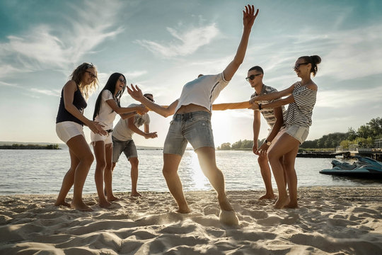 Friends funny game on the beach under sunset sunlight.