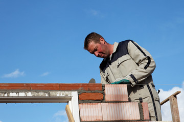 mason buids wall along a masonry wire under blue sky
