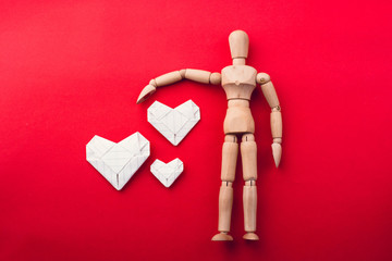 wooden dummy and paper harte on red background,love concept