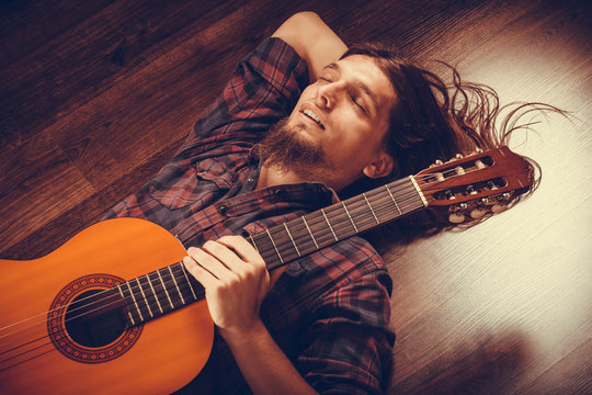 Relaxed man on the floor with guitar.