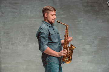 Obraz na płótnie Canvas Happy saxophonist with sax over gray background