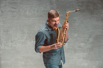 Happy saxophonist with sax over gray background
