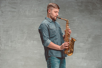 Fototapeta na wymiar Happy saxophonist playing music on sax over gray background