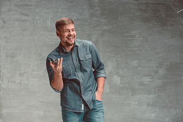 The young smiling caucasian businessman on gray background with phone