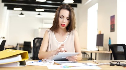 Young business woman sitting in her office and using a tablet computer
 - Powered by Adobe