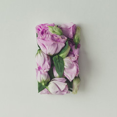 Pink flowers in shape of a gift box on bright background. Flat l