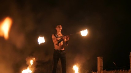 Fire show performance. Three handsome male fire performers dance twirling two fire batons staff ignited from both sides each. Slow motion