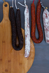 Mix of Cured meat and sausages hanging on dark wooden background