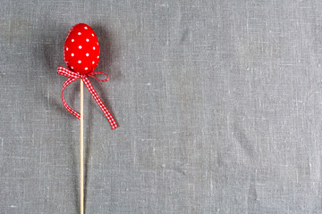 Red egg on a stick on a gray background