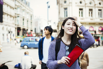 Young Japanese man and woman enjoying a day out in London, walking near Piccadilly Circus.