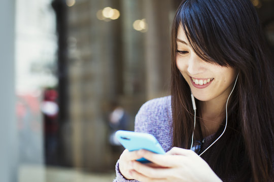 Young Japanese Woman Enjoying A Day Out In London, Using A Smartphone.