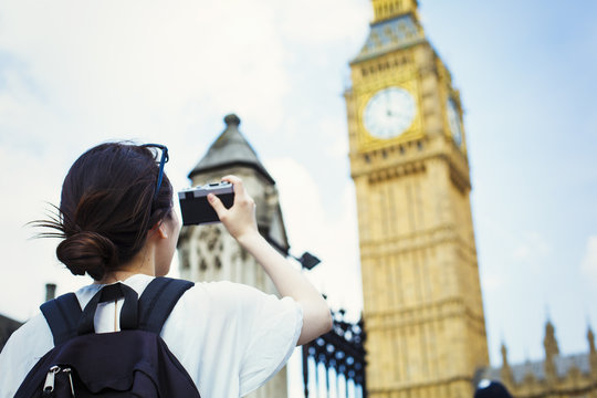 Young Japanese woman enjoying a day out in London, taking a picture of Big Ben.