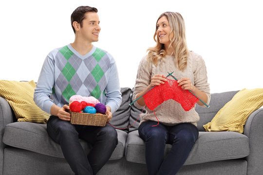 Man and woman knitting together on a sofa