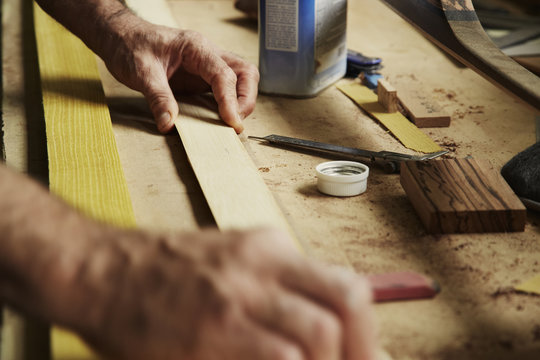 A carpenter at a workbench holding a piece of wood. 