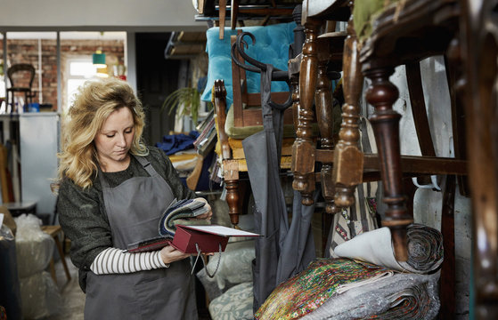 A woman flicking through a fabric sample book, looking at colours and patterns. 