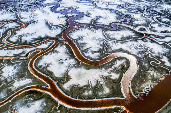 Aerial view of the landscape, meandering water channels and the salt pans with white salt and mineral deposits at Alvisio. 