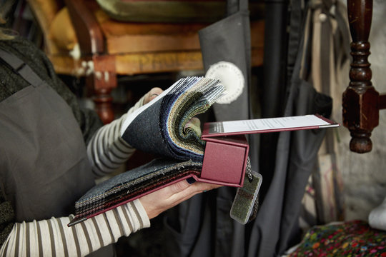 A person flicking through a fabric sample book, looking at colours and patterns. 