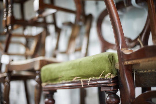 A stack of antique chairs, with fraying seas for refurbishment. 