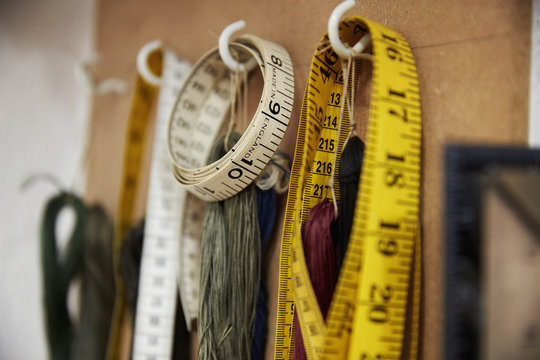 A row of hooks and tape measures on a tool board. 